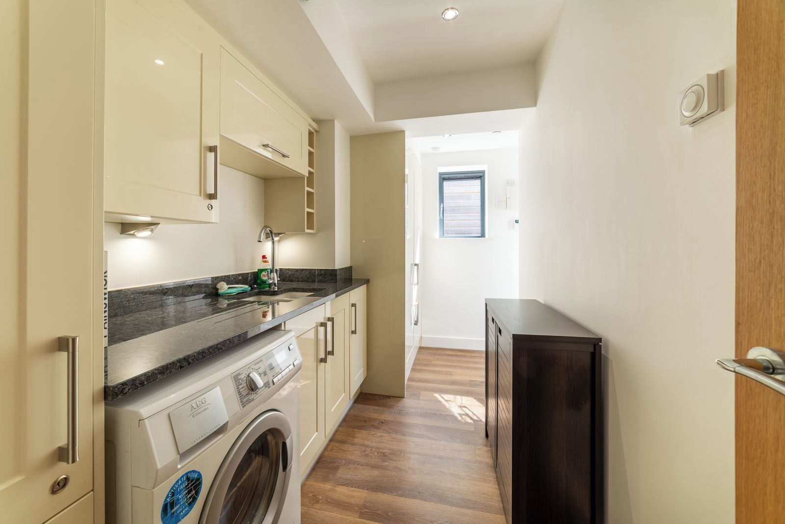 A compact kitchen with a washing machine, a sink, and a small cabinet.