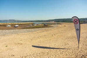 Une plage de sable avec des bateaux et un panneau indiquant qu’il est interdit de se baigner.