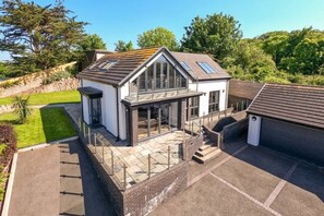 A modern house with a large glass window, a balcony, and a garage.