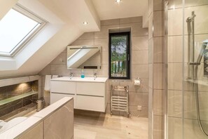 A modern bathroom with a skylight, a glass shower enclosure, and a built-in vanity.