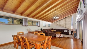 Relax in this inviting living space with a dining table, comfortable sofa, and large windows offering a view of the outdoors.