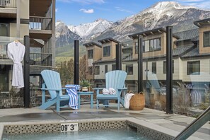 A pool area with two Adirondack chairs, a small table, and a hot tub. - Spring Creek Condo, Hot Tub & Mountain Views – Sleeps 7, Walk to Downtown (Canmore)