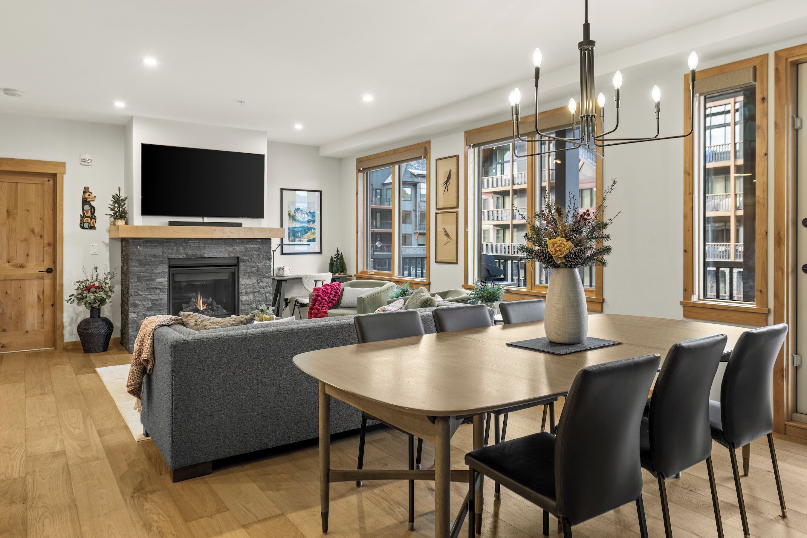 Una sala de estar moderna con chimenea, televisor grande y comedor con sillas y mesa.