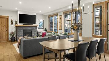 Una sala de estar moderna con chimenea, televisor grande y comedor con sillas y mesa.