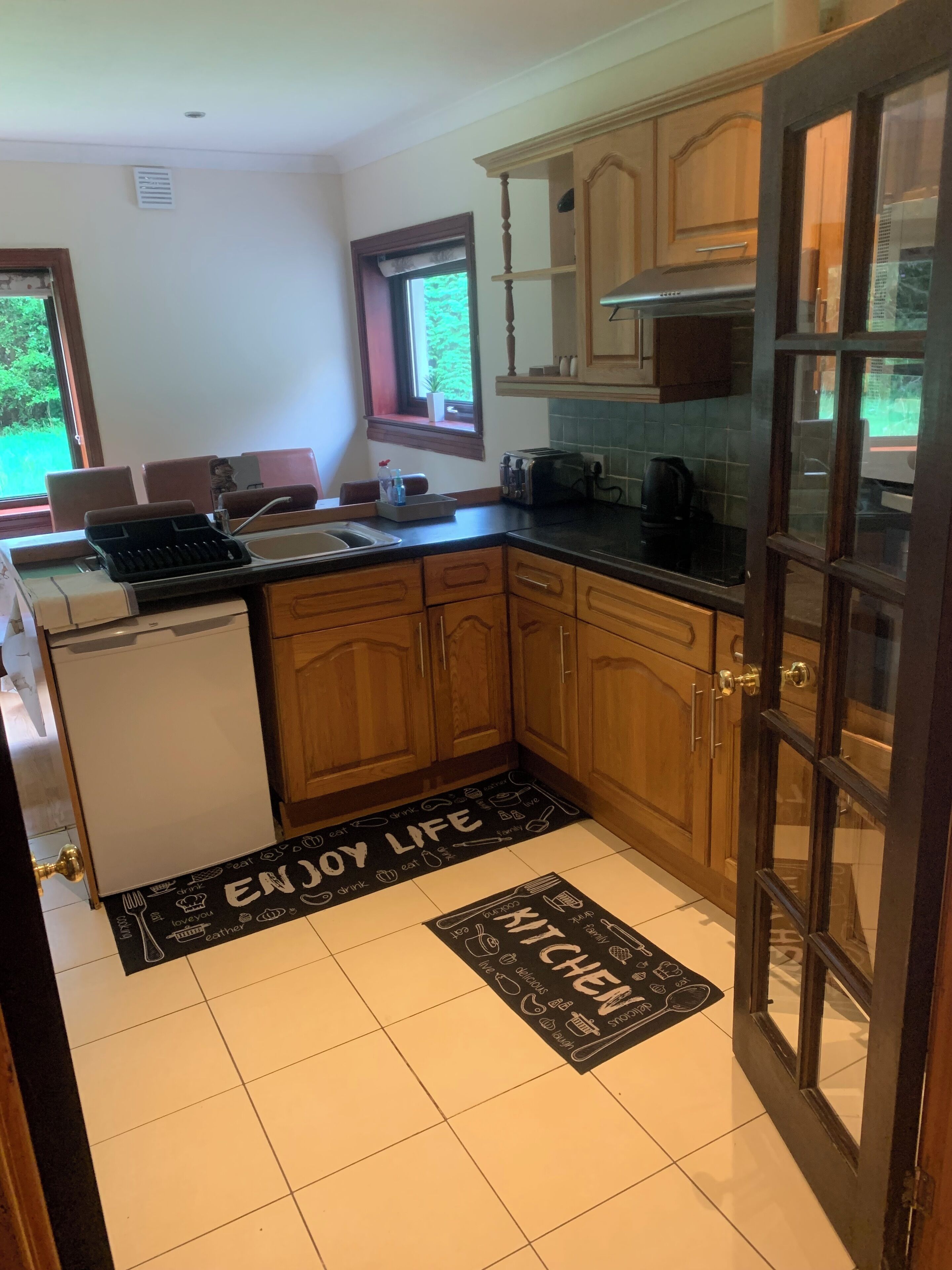 A kitchen with wooden cabinets, a black countertop, a built-in oven, and a window.