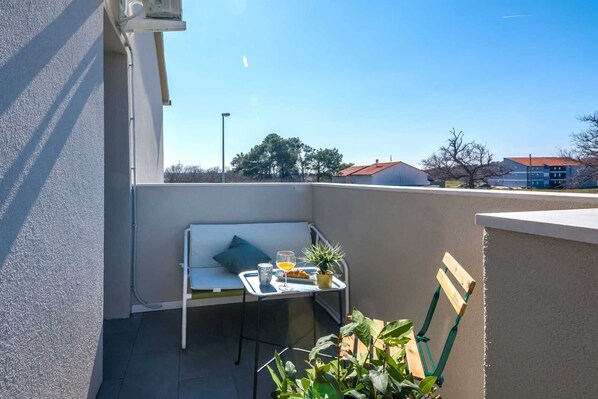 Relax on this balcony with a table, chair, and potted plant, perfect for a casual meal or quiet moment.