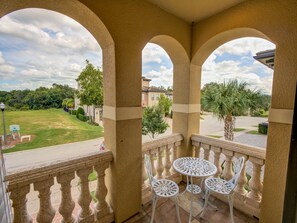 A balcony with a view of a residential area, including houses and a lawn.