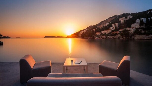 A sunset view from a seaside terrace with two armchairs and a small table. - Exclusive Apartment Lara - One Bedroom Apartment with Balcony (Dubrovnik)