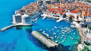 A coastal town with historic architecture, a fortified castle, and a marina with numerous boats. - Exclusive Apartment Lara - One Bedroom Apartment with Balcony (Dubrovnik)