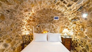 Een bed in een kamer met een stenen muur.