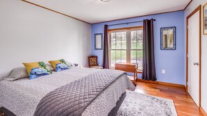 Un dormitorio con una cama grande, una ventana con cortinas, piso de madera y una puerta.