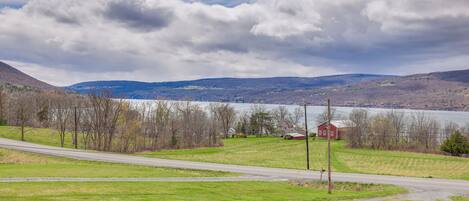 A rural landscape with a road, a small red building, and a lake in the distance.