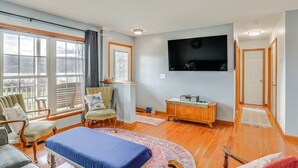 Una habitación amplia con una cama grande, dos sillones, un aparador de madera y un televisor montado en la pared.