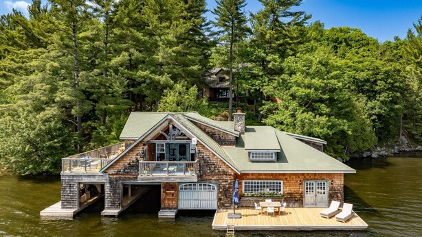 A lakeside cabin with a dock, a covered deck, and a large window overlooking the water.
