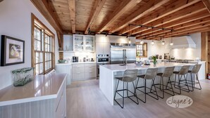 A modern kitchen with a large island, wooden beams, and bar stools.
