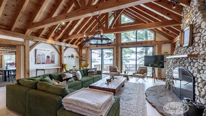 A spacious living area with a green sectional sofa, a wooden coffee table, and a stone fireplace.