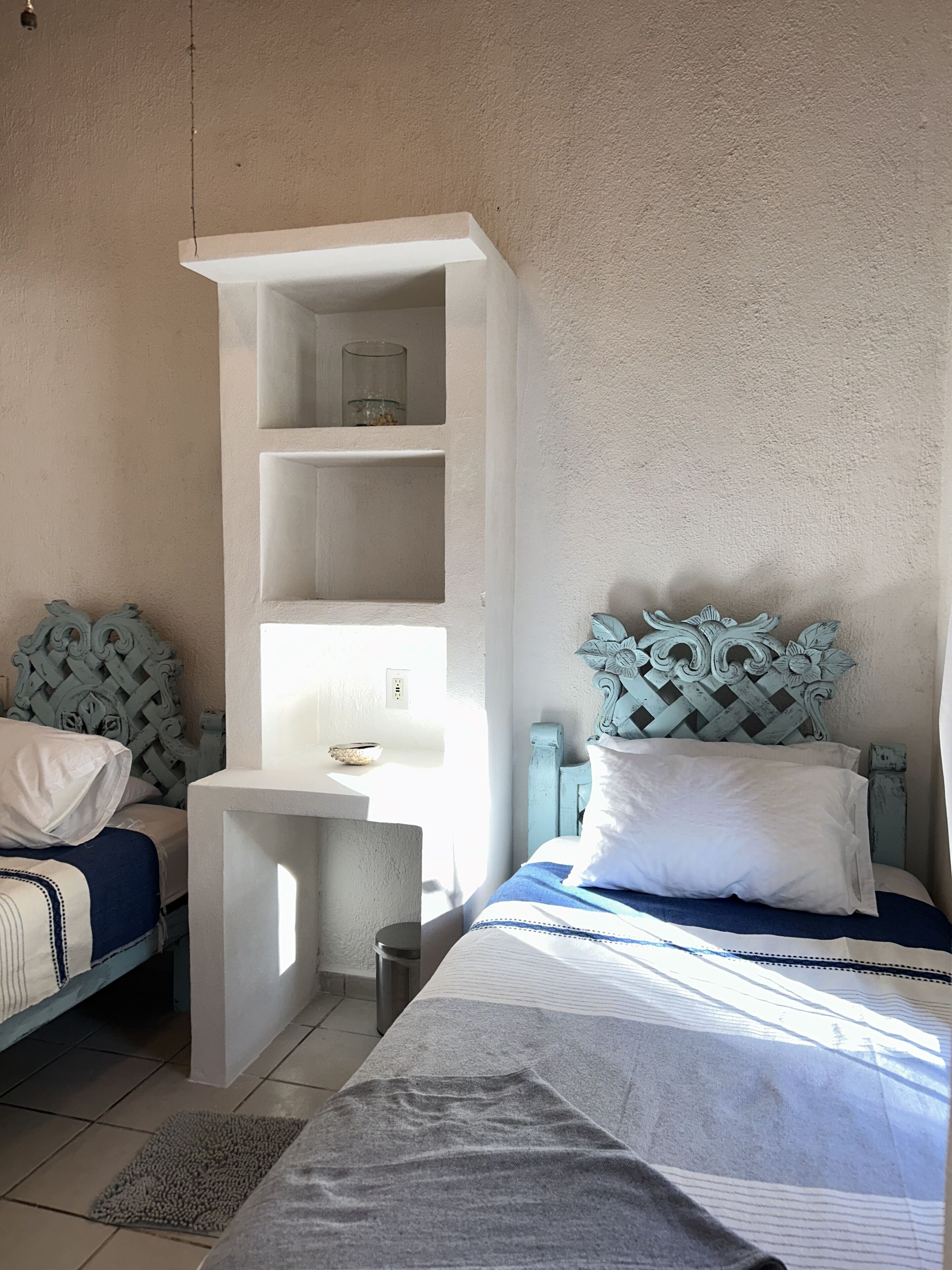 A bedroom with two beds, a small desk, and a decorative headboard.