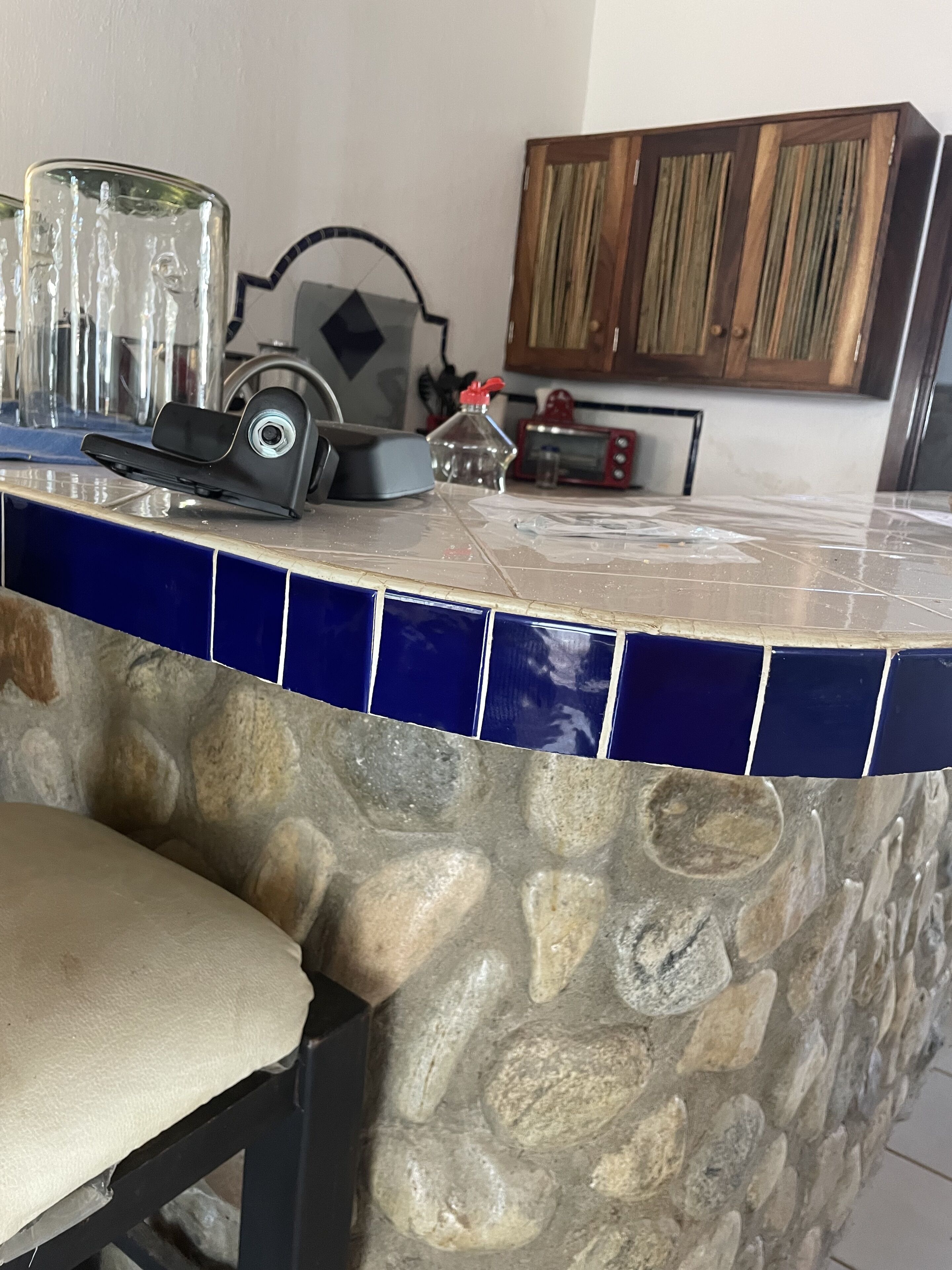 Uma bancada de cozinha com painel de pedra, micro-ondas, torradeira e um pequeno armário.
