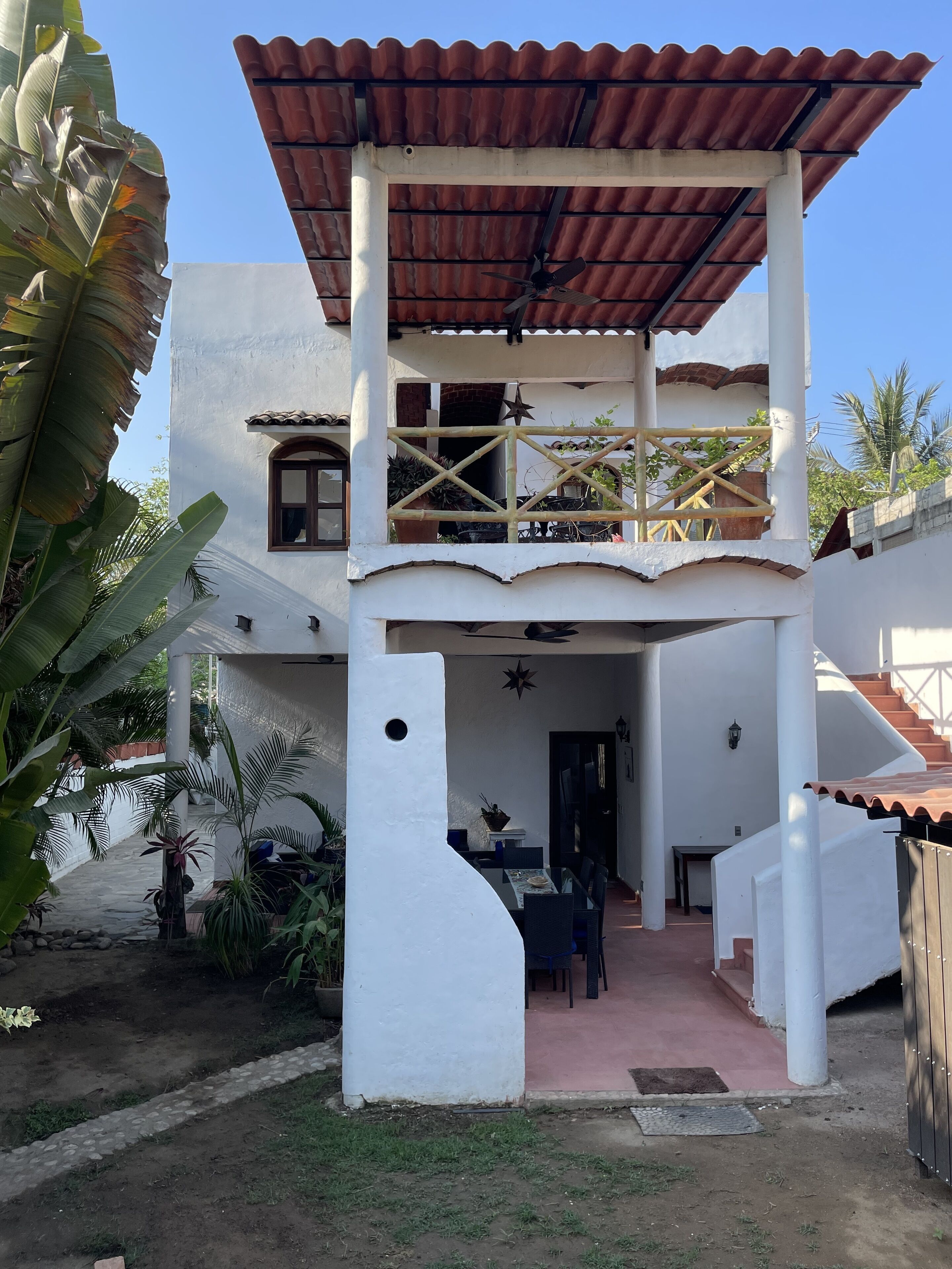A two-story house with a balcony, a staircase, and a patio area.