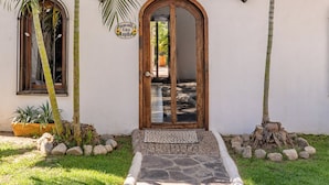 A building with a white exterior, a wooden door, and a stone pathway leading to the entrance.
