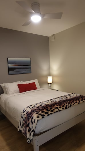 A bedroom with a bed, a ceiling fan, a wall-mounted lamp, and a framed picture. - Spacious Patio and Funky Vibes in Old Town! (Victoria)
