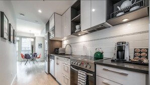 A modern kitchen with white cabinets, a stainless steel stove, and a coffee maker. - Spacious Patio and Funky Vibes in Old Town! (Victoria)