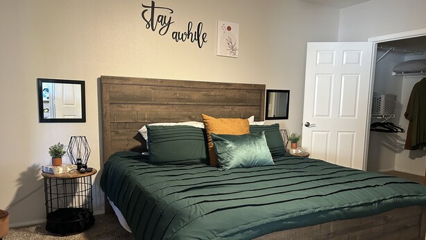 Une chambre à coucher avec une tête de lit en bois, une couvre-lit verte et une décoration murale invitant à la détente.