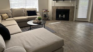 Un salon comprenant un canapé, une table basse, une cheminée et un téléviseur fixé au mur.