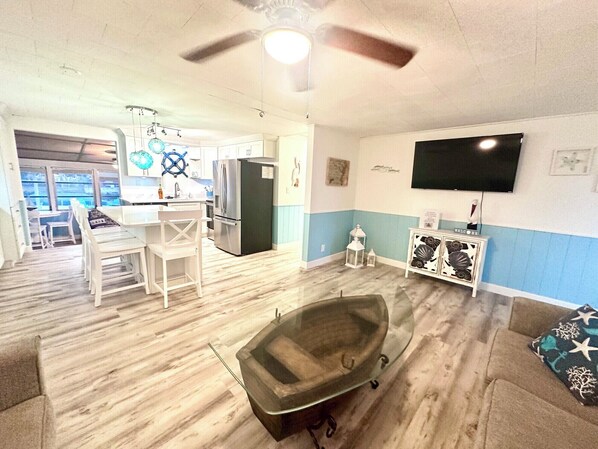 A compact living space with a kitchenette, a dining area, a seating area with a bathtub, and a TV mounted on the wall.