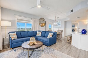 A modern living room with a blue sectional sofa, a round coffee table, and a view of the city.