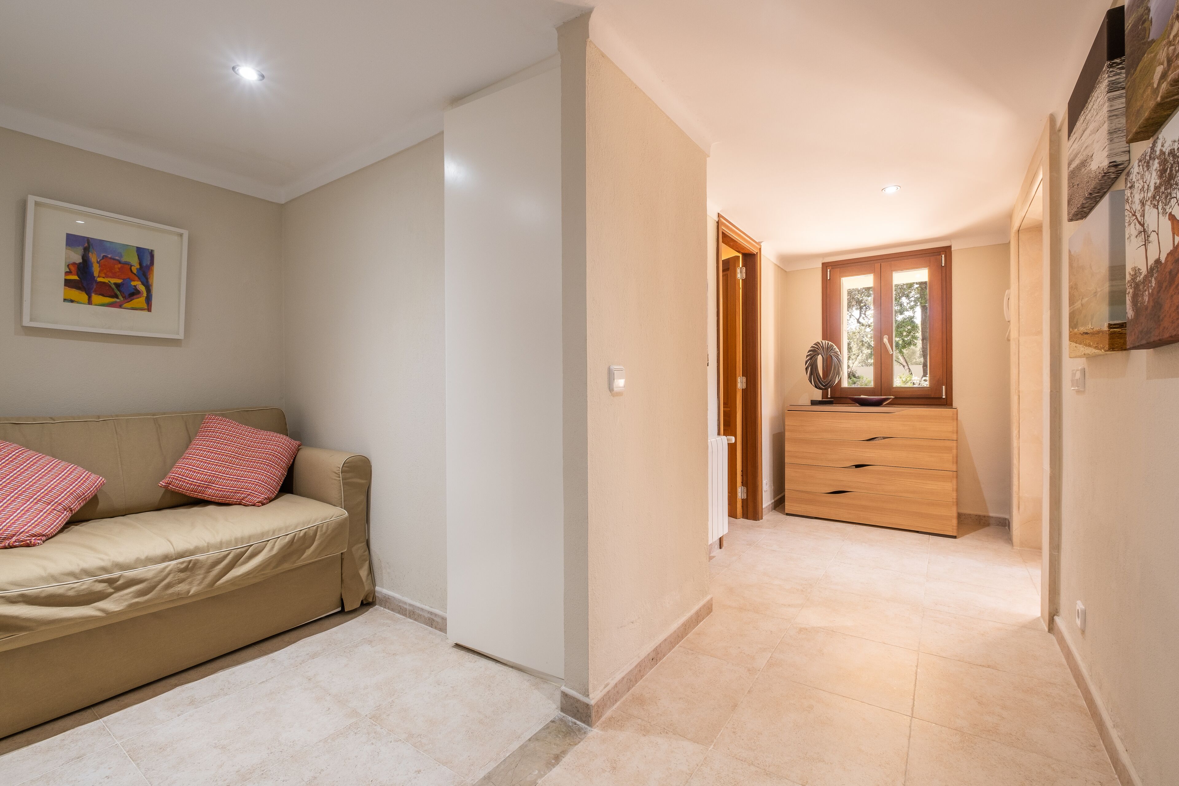 A hallway with a beige sofa, a wooden dresser, and a framed picture on the wall.