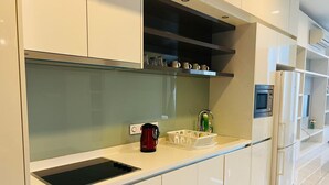 A modern kitchen with white cabinets, a stainless steel range hood, a built-in sink, and a refrigerator.