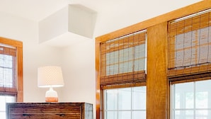 Ein Schlafzimmer mit einem großen Bett, einem Holzkopfende und einem Fenster mit Bambusrollos.