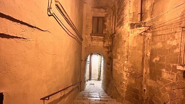 A narrow stone staircase leading up to a door at the end of a dimly lit corridor. - Accogliente Casa per Famiglie, Gruppi e Animali Domestici (Matera)
