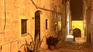 A narrow cobblestone street flanked by old buildings with arched doorways and windows. - Accogliente Casa per Famiglie, Gruppi e Animali Domestici (Matera)