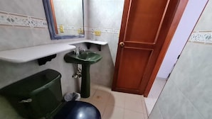 A small bathroom with a toilet, green sink, and a mirror above the sink. - Casa Inca Inca  (Santa Marta)