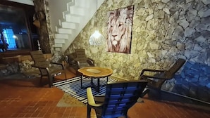 A stone-walled lounge area with a lion mural, a round table, and several chairs. - Casa Inca Inca  (Santa Marta)