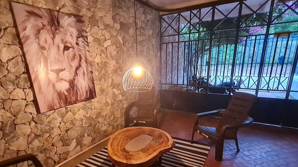 A stone wall with a lion painting, a round wooden table, and two chairs. - Casa Inca Inca  (Santa Marta)