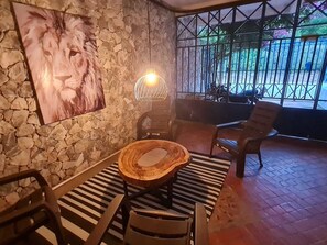 Una pared de piedra con un león pintado, una mesa de madera redonda y dos sillas.