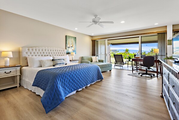 A spacious bedroom with a large bed, a balcony with a view, and a ceiling fan.