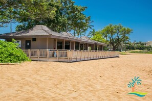 A beachside building with a covered porch and a sandy beach in the foreground.