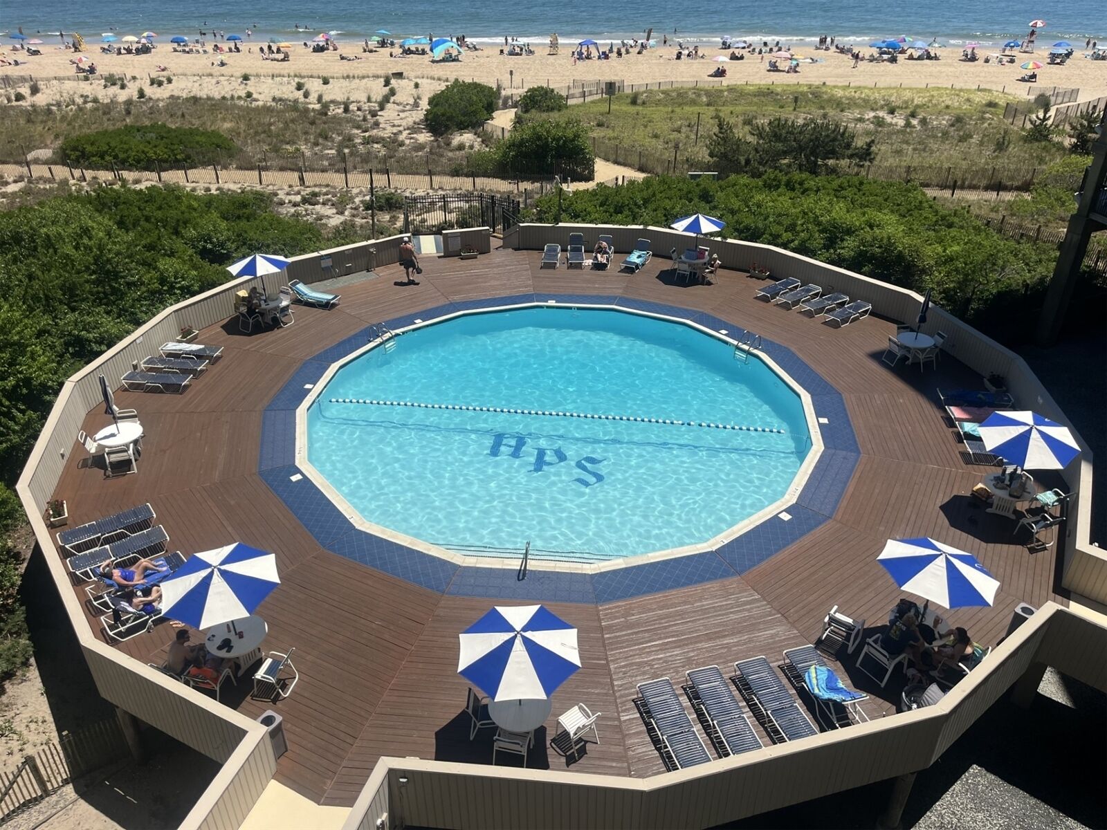 A circular swimming pool with a deck surrounding it, equipped with sun loungers and umbrellas.