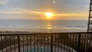A balcony with a view of the ocean at sunset.