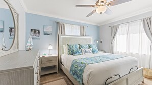 A bedroom with a bed, nightstands, a dresser, a ceiling fan, and artwork on the walls.