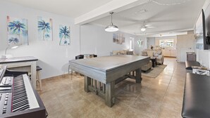 A spacious living area with a large wooden table, a piano, and artwork on the walls.