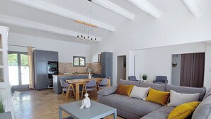 A modern living room with a grey sectional sofa, a coffee table, and a dining area with a wooden table and chairs.