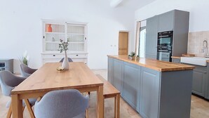 A modern kitchen with grey cabinets, a wooden island, and a built-in oven.