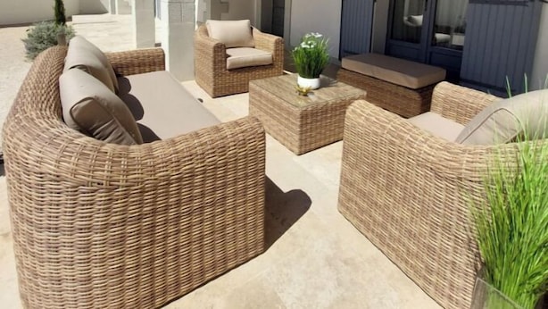 An outdoor seating area with wicker furniture and a potted plant.