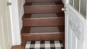 A wooden staircase with a black and white patterned rug at the bottom.