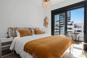 Une chambre moderne avec un grand lit, une table de chevet, une lampe et une vue sur la ville grâce à une grande fenêtre.